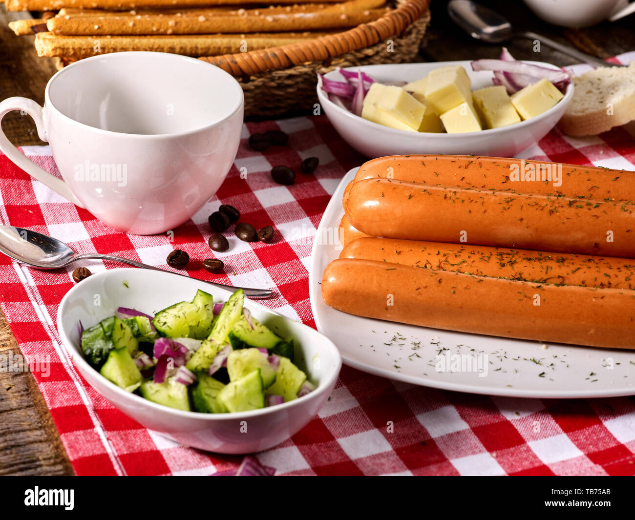 Sausage portion with baguette on table setting on checkered cloth Stock Photo