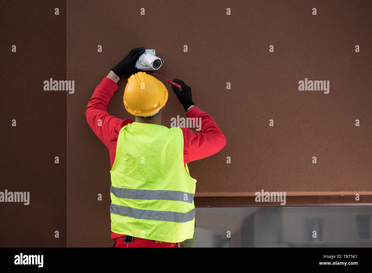 Professional cctv technician working.Technician Fixing Camera On Wall Stock Photo