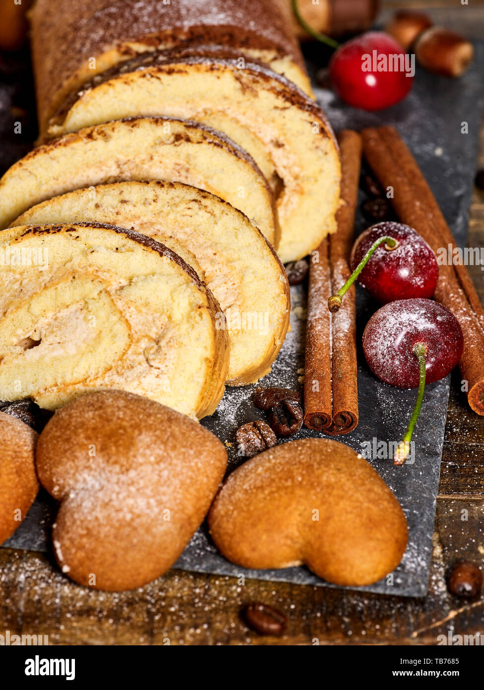 Sand cookies heart shape , rolled cake with cherry, cinnamon stick Stock Photo
