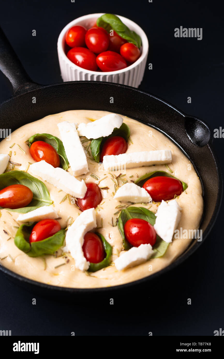 Food concept rising dough for Homemade organic Focaccia in skillet iron pan on black background with copy space Stock Photo