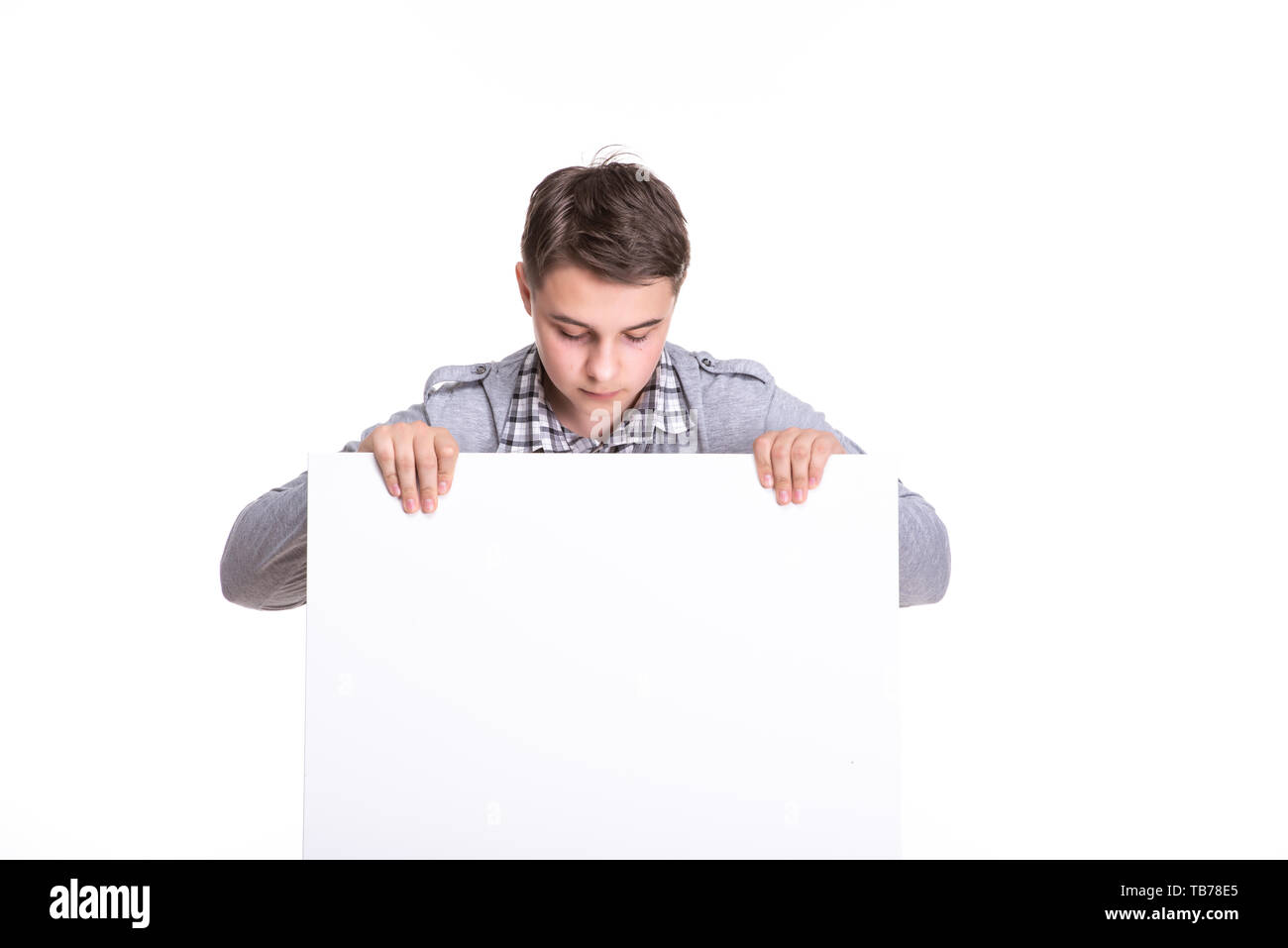 Close up of man showing white board. Guy teenager, student, schoolboy showing empty space white placard. Stock Photo