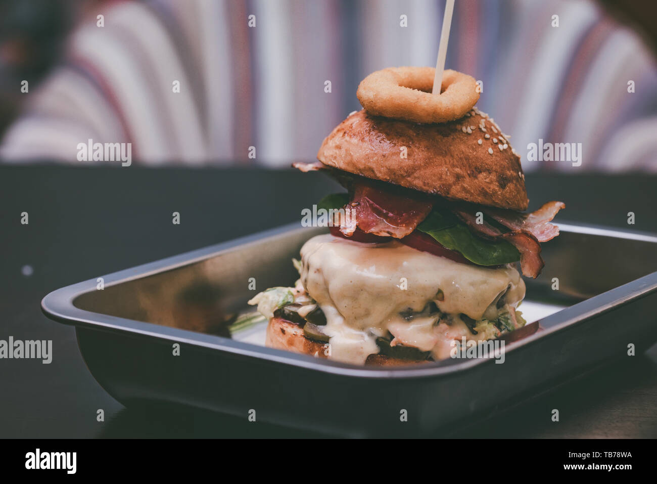 Close up tall tasty burger with cheese served on tray Stock Photo
