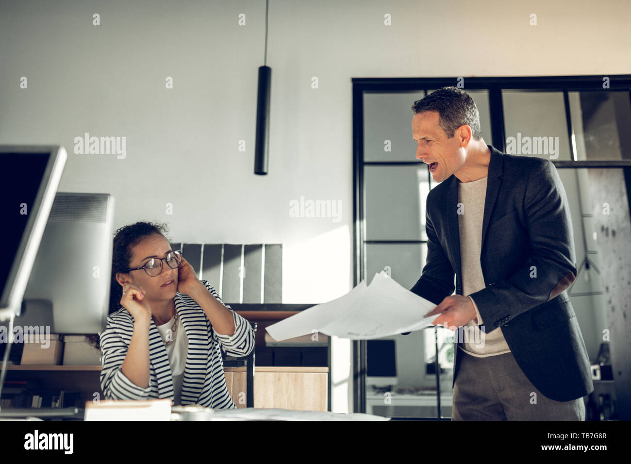 Mature boss shouting at his young trainee for not finishing task Stock Photo