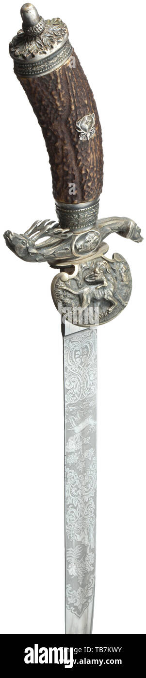 A hunting hanger of the German Hunting Association in special deluxe issue, maker Clemen & Jung, Solingen, The nickel-plated wedge blade with double-edged tip is finely etched with scenes of deer, fox and boar. The ricasso with in-struck maker's name and mark. The guard plate with retriever dogs in high relief, the quillion ends with stag and dog heads, the pommel cap with a modelled oak leaf finial in silvered (somewhat rubbed) non-ferrous metal. Stag horn grip with applied, silvered DJ-emblem, green leather scabbard with silvered fittings, the , Additional-Rights-Clearance-Info-Not-Available Stock Photo