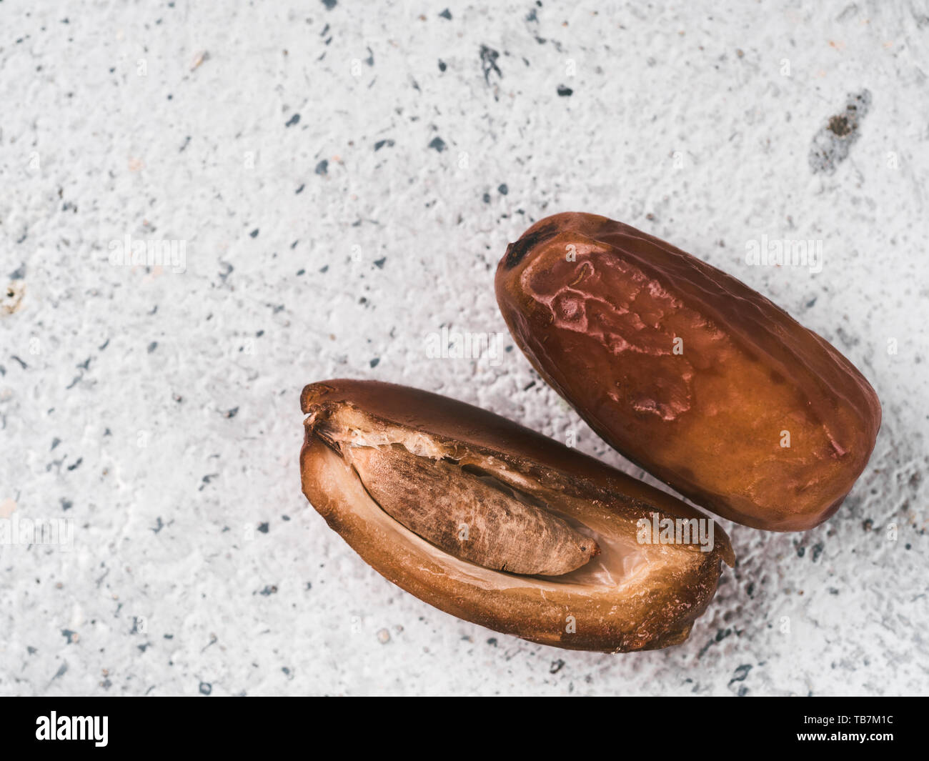 Sweet raw dates on gray cement background. Whole dates and half with bone date on grey concrete surface. Sugar free alternatives concept with space for text. Top view. Extreme close up view Stock Photo
