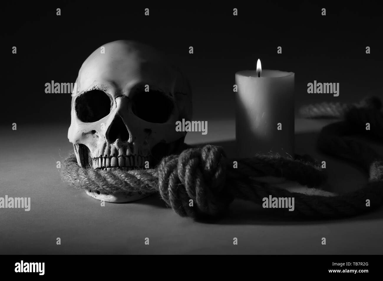 Human skull, rope and burning candle on dark background Stock Photo Alamy