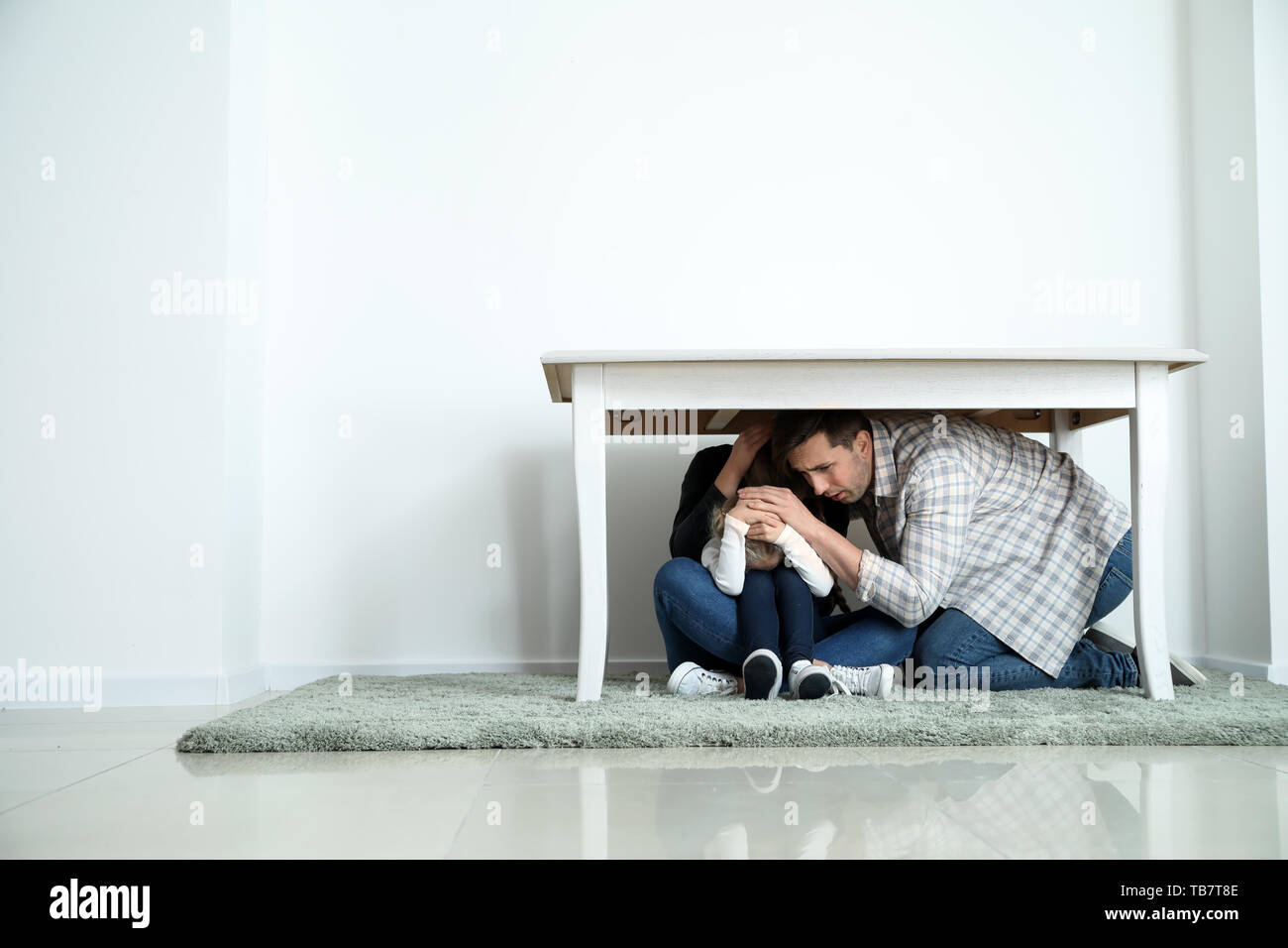 Family under table during earthquake indoors Stock Photo Alamy