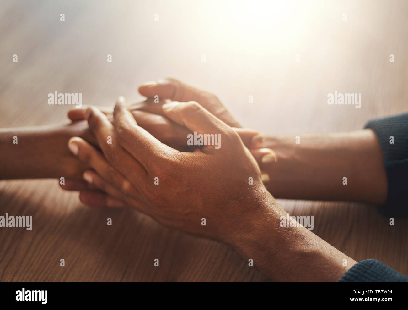 Couple's hand holding hands on wooden desk Stock Photo