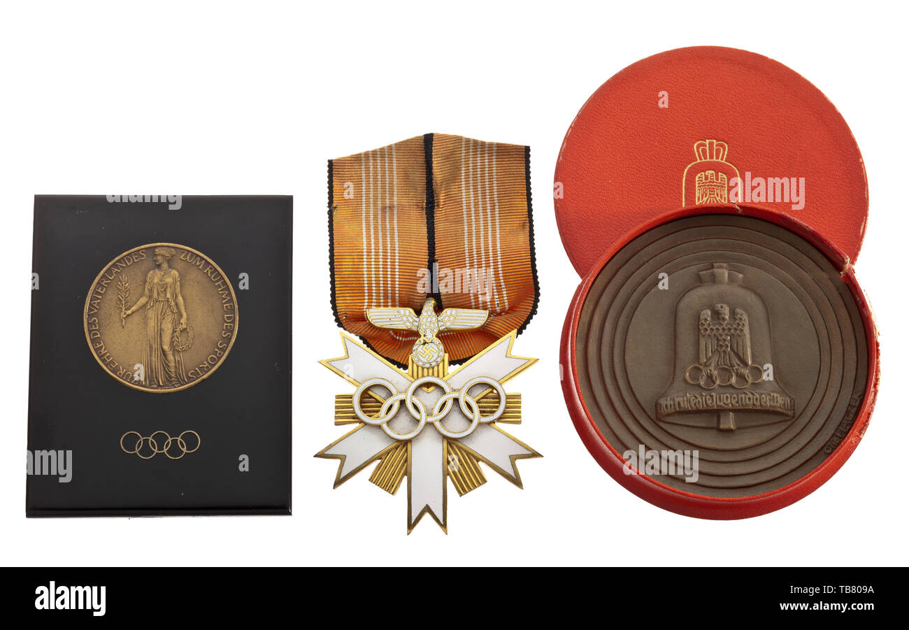 Four objects commemorating the Olympic Games 1936, A German Olympic Decoration, 2nd Class, on ribbon. Includes a relief plaque in bronze by Otto Placzek, inscribed 'XI. Olympiade Berlin 1936' on the front, the Olympic bell and the artist's signature on the back, in a red leather, gold-embossed presentation case (diameter circa 7.5 cm). Comes with a stand (black plastic) with inlaid bronze medal, inscribed 'Zur Ehre des Vaterlandes / zum Ruhme des Sports' (tr. For the honour of our country and for the glory of sport) on the front, the Olympic bell on the back (total height 7, Editorial-Use-Only Stock Photo