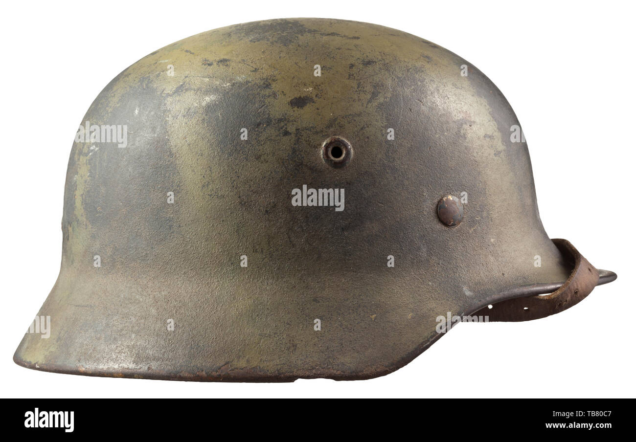 A steel helmet M 40 for members of Luftwaffe field divisions, The interior of the skull with maker's mark 'Q64' (Quist, Esslingen), green-toned camouflage paint covering the Luftwaffe-grey paint, the Luftwaffe eagle clearly visible. Complete with inner liner and chinstrap. Very rare camouflage. historic, historical 20th century, Editorial-Use-Only Stock Photo