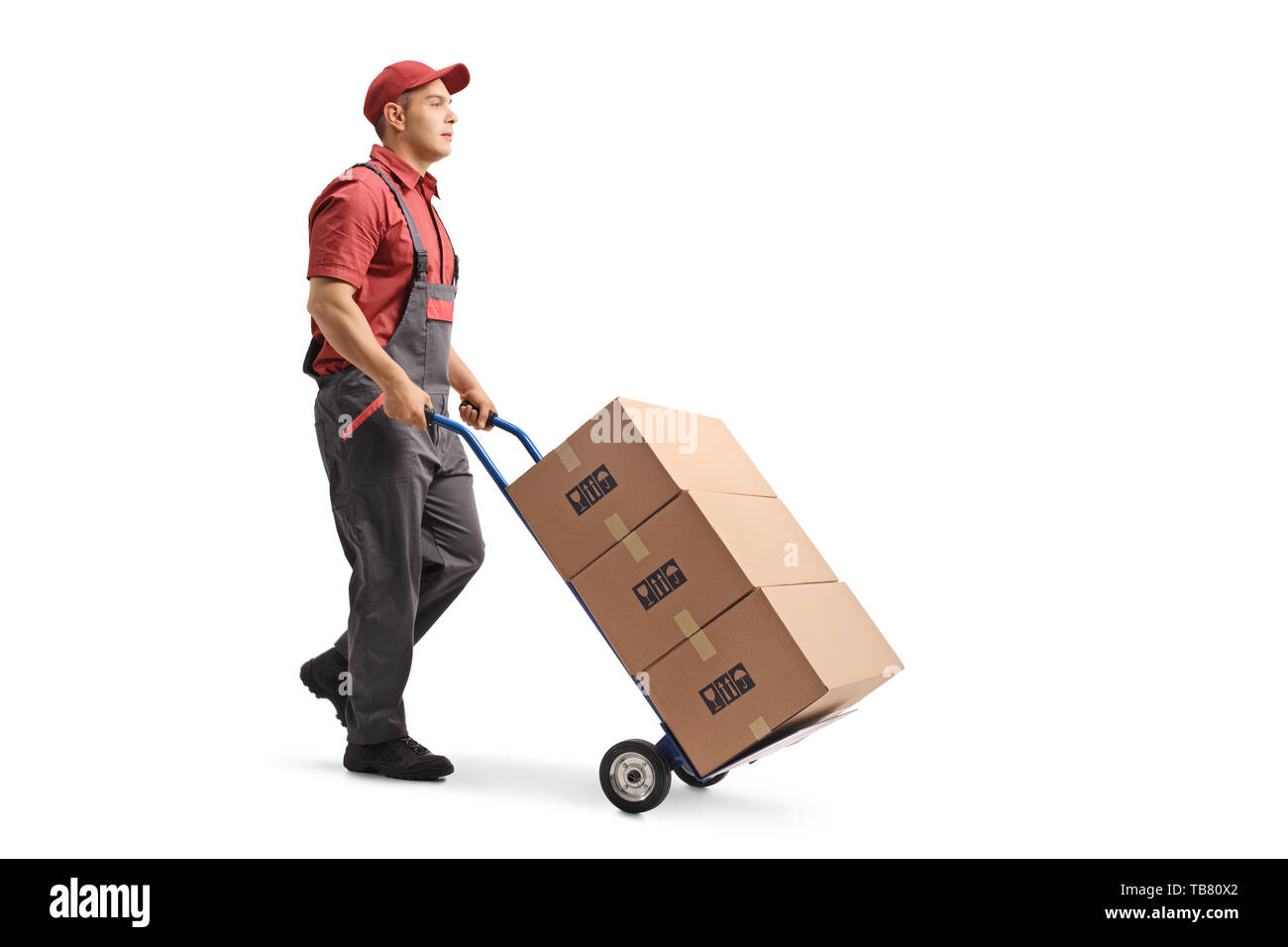 Full length shot of a young male worker in a uniform pushing boxes on a hand truck isolated on white background Stock Photo