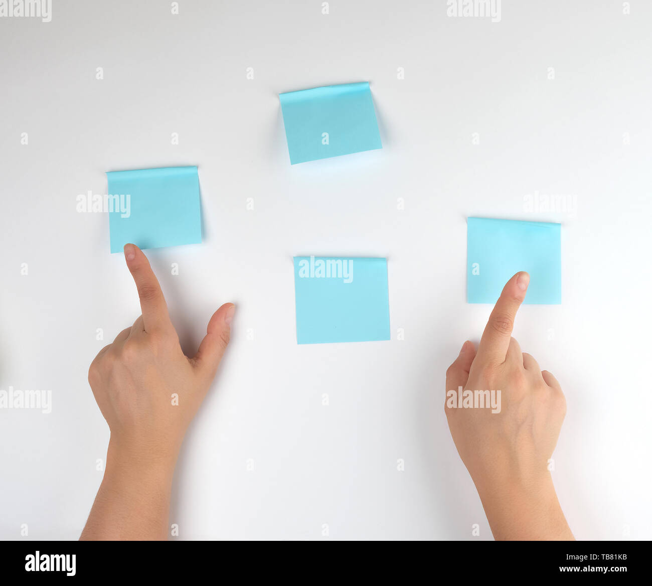 lot of blue stickers on a white background and two female hands pointing at them, conceptual background Stock Photo