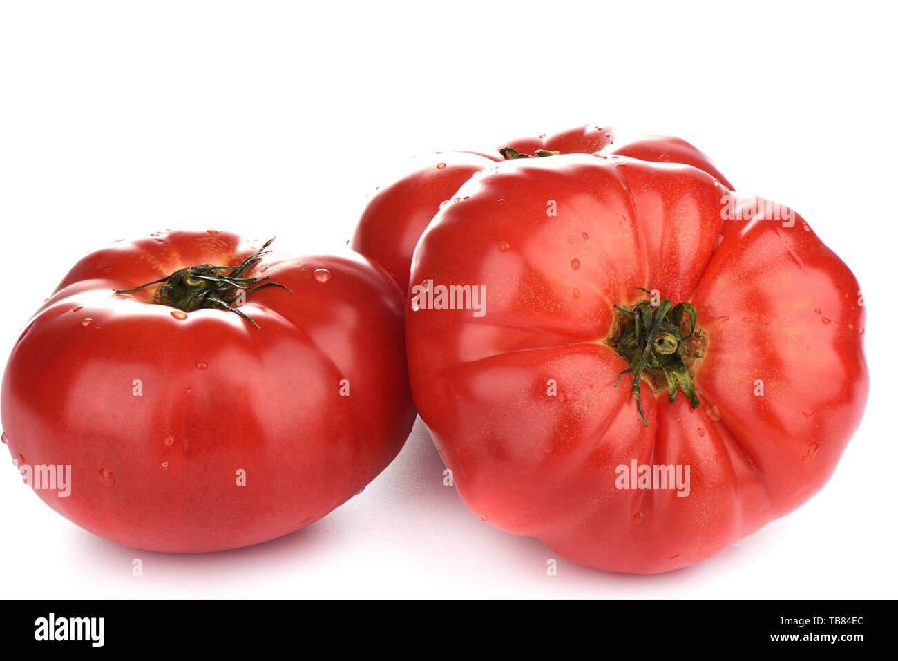 Three ripe big tomatoes with water drops isolated on white background ...