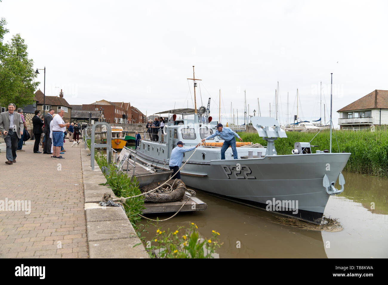 Man standing on deck of boat, P22, a US built Rhine River Patrol boat from the 1950's, casting off by untying and handing the mooring rope to another man on pontoon. P22 just about to leave Sandwich quay side for France to take part in the 75th anniversary of D-Day. Stock Photo