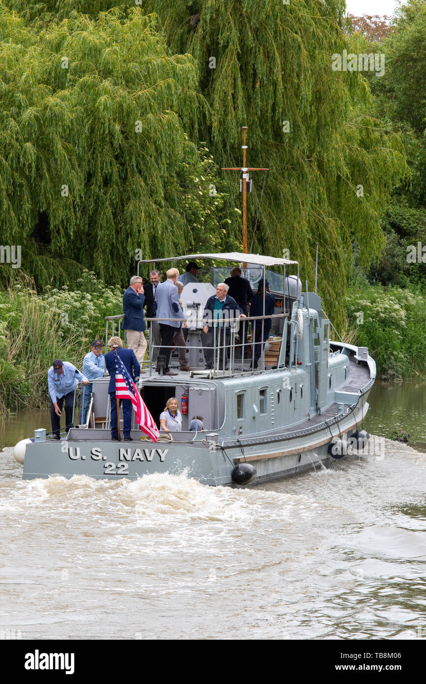 The P22, former US built Rhine River Patrol Boat, leaves Sandwich with a select crew on the first stage of a journey to France for the 75th anniversary of D-Day in June 2019. Stern of patrol boat as it cruises down river past trees. US flag flying from stern, several people standing on decks. Stock Photo