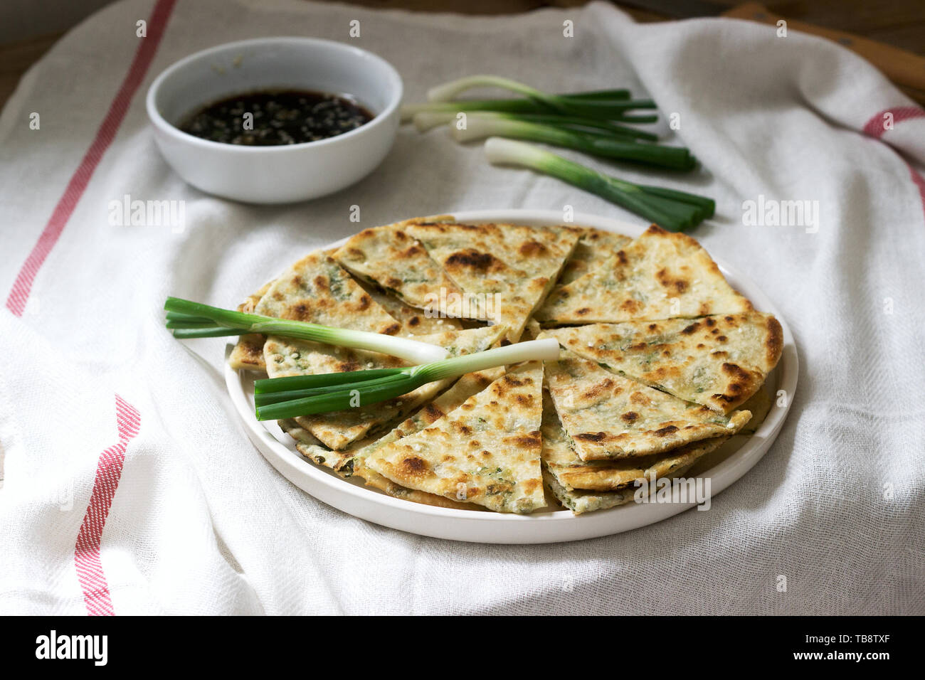 Homemade appetizing scallion pancakes and a bunch of green onions. Rustic style. Stock Photo