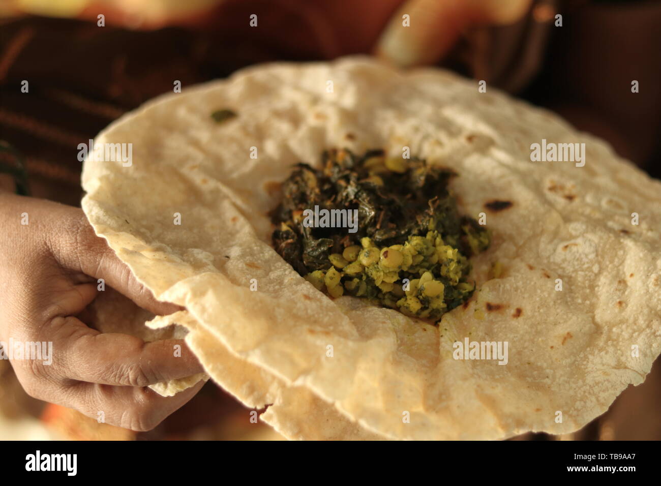 Closeup of woman eating South Indian north Karnataka peoples daily healhy breakfast Jowar roti or rotti or bhakri with dal curry in hand without using Stock Photo