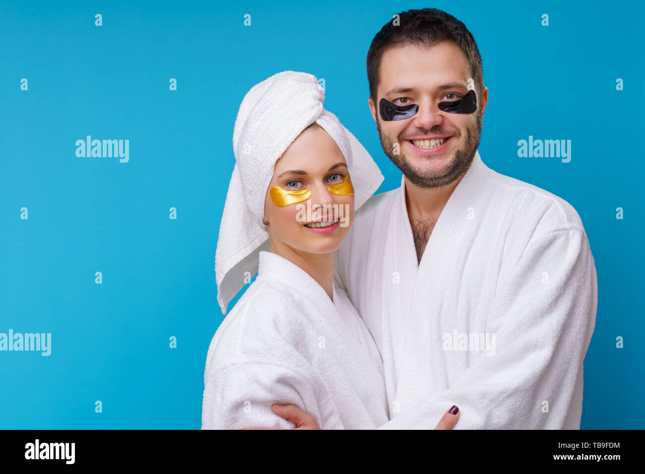 Photo of man and woman with gel pads under eyes and in white robe Stock Photo