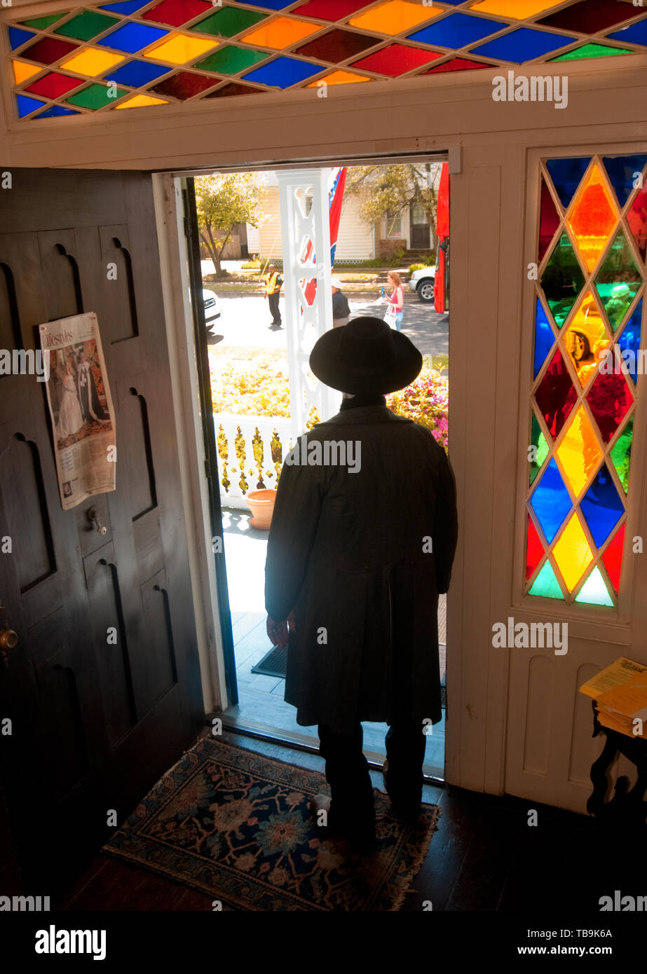 A homeowner, dressed in period antebellum costume, is silhouetted as he gazes out the door of the Amzi Love Home in Columbus, Mississippi. Stock Photo