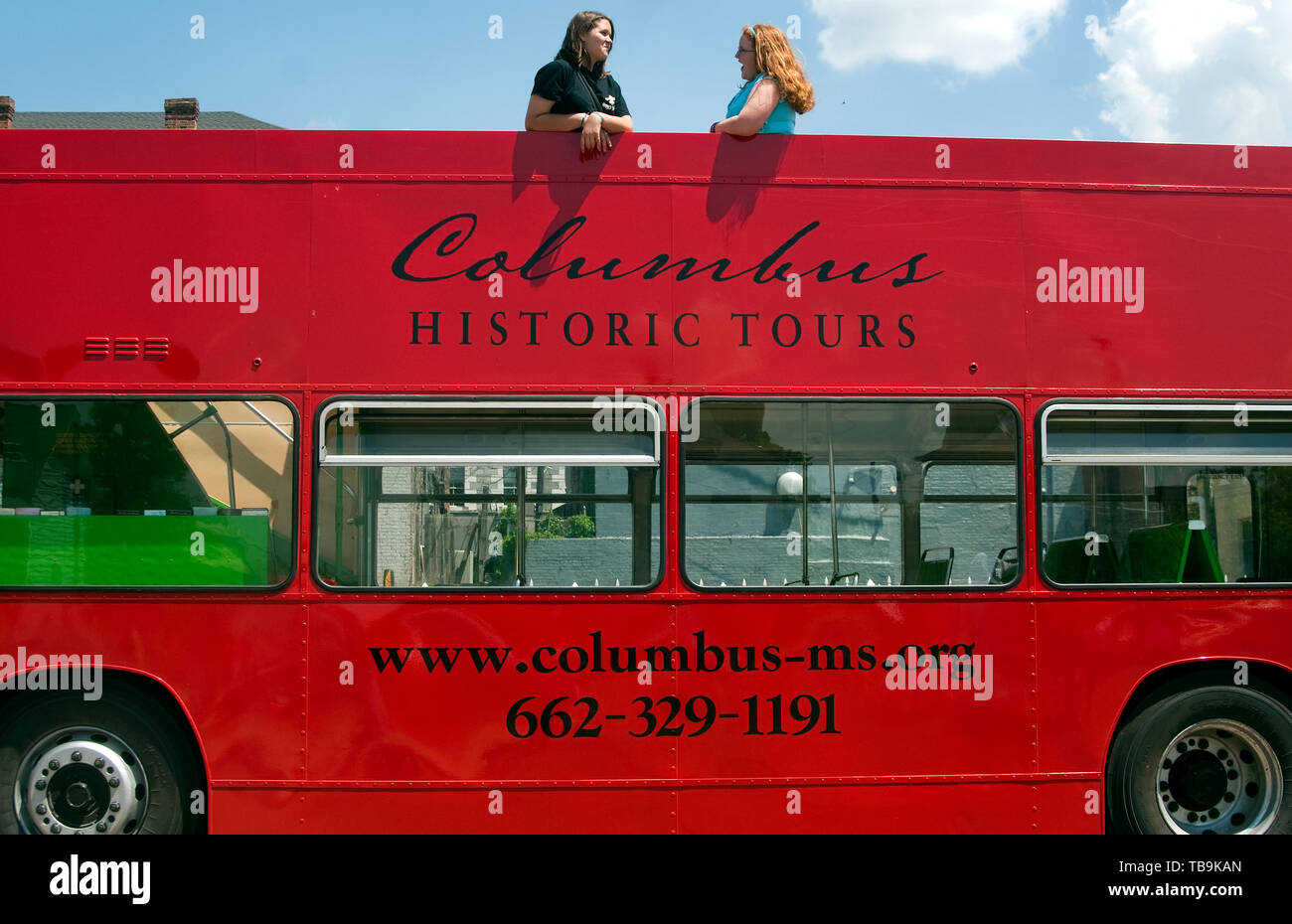 Tourists chat as they stand on the top level of a double-decker tour bus parked outside the Tennessee Williams Welcome Center in Columbus, Mississippi. Stock Photo