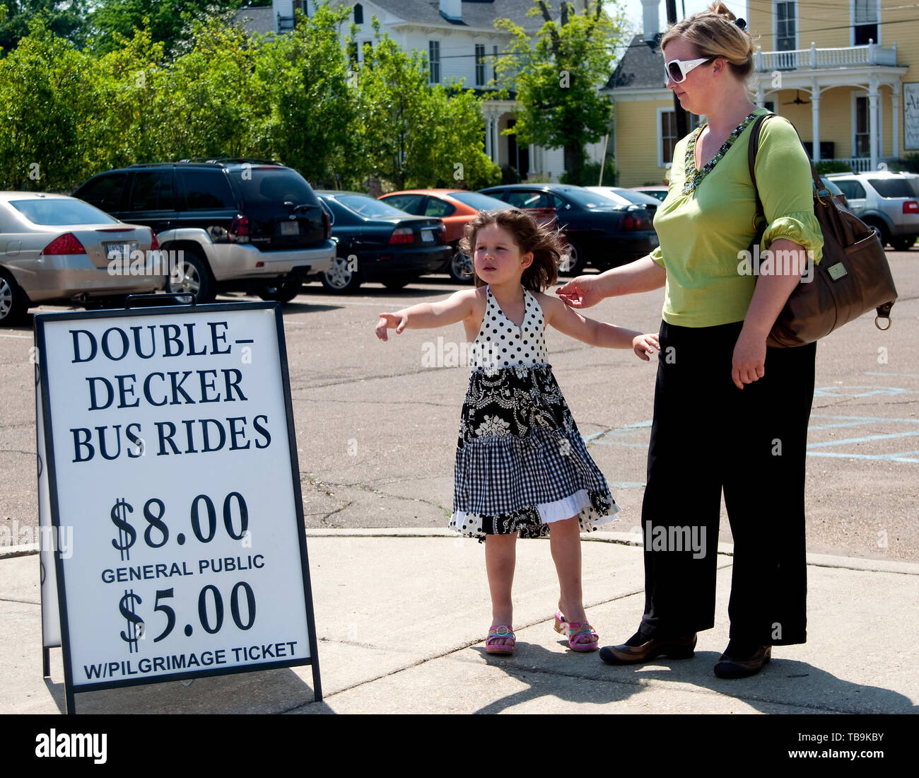 A child points to a double-decker tour bus as she waits for a ride with her mother in Columbus, Mississippi. Stock Photo