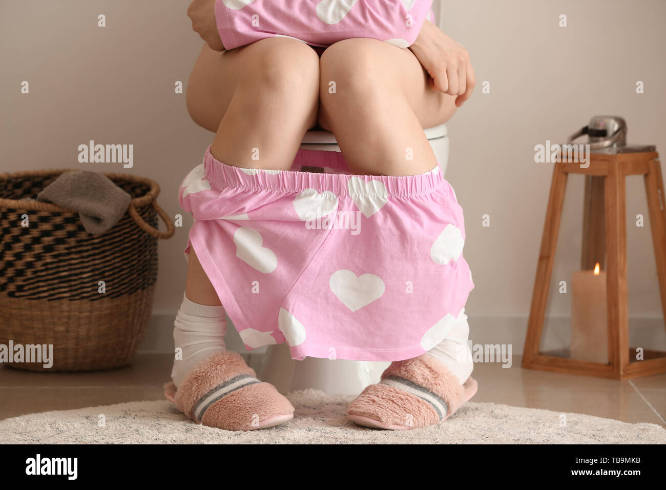 Young woman sitting on toilet bowl in restroom Stock Photo Alamy