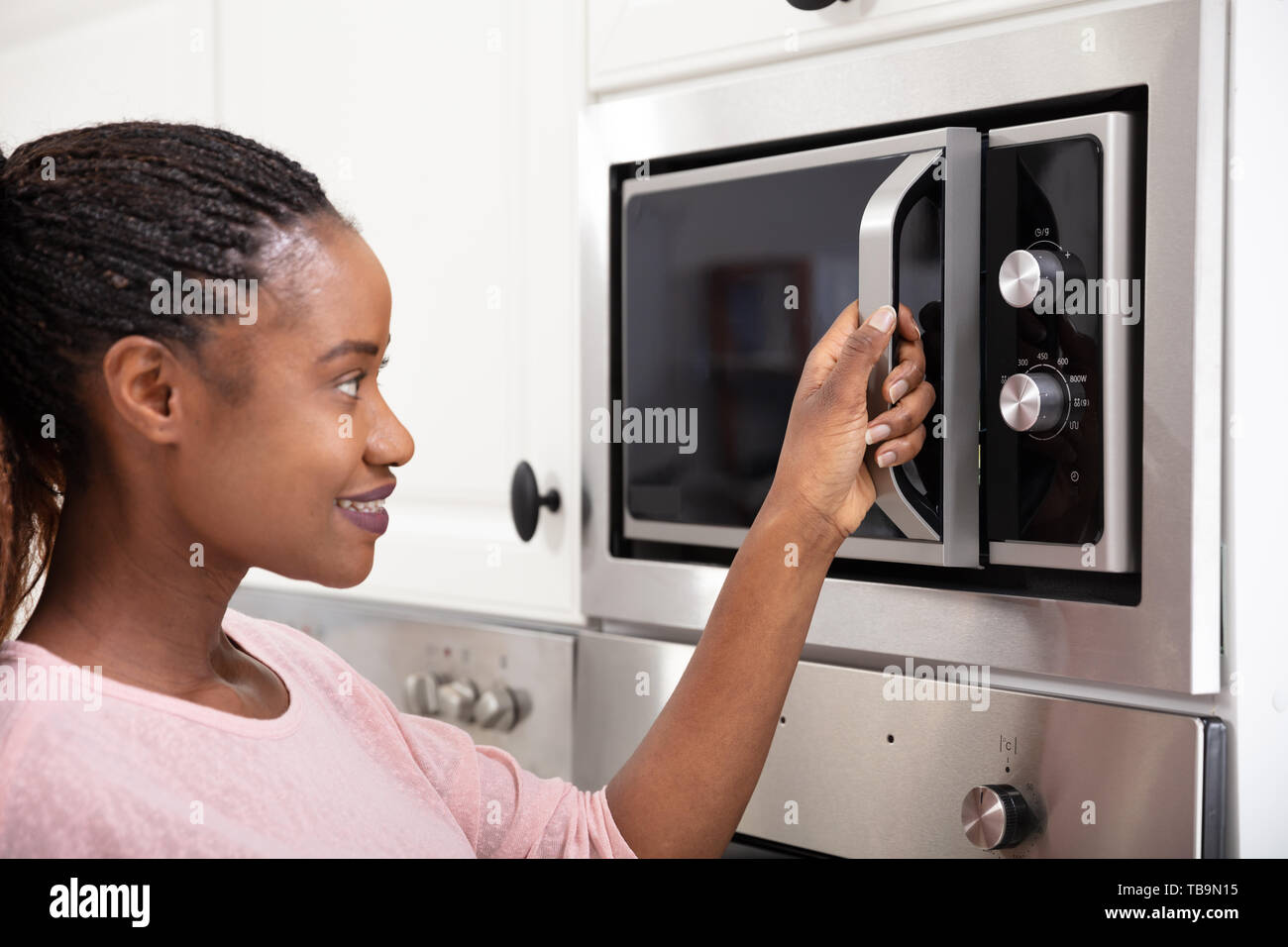 Close-up Of African Women Hand Opening The Oven Door Stock Photo