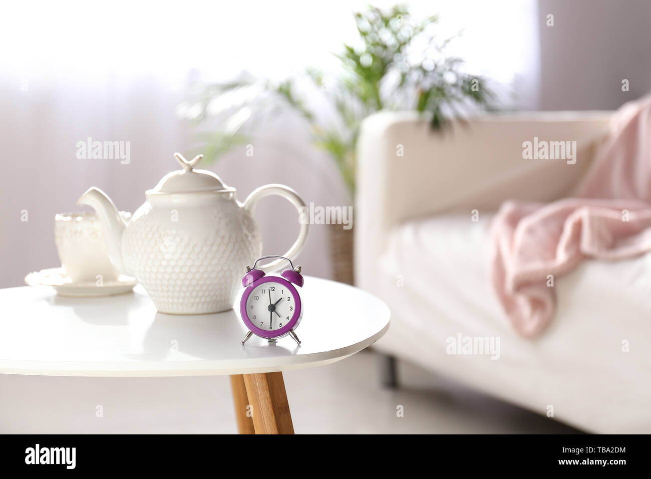 Alarm clock, teapot and cup on table in light room Stock Photo Alamy