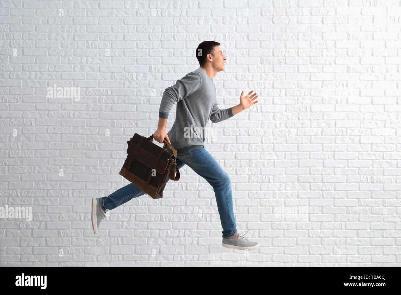 Running man with briefcase against white brick wall Stock Photo Alamy