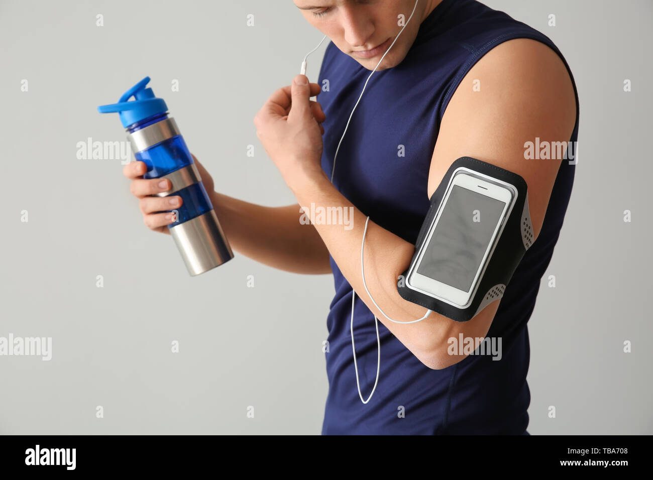 Sporty young man with bottle of water against light background Stock ...