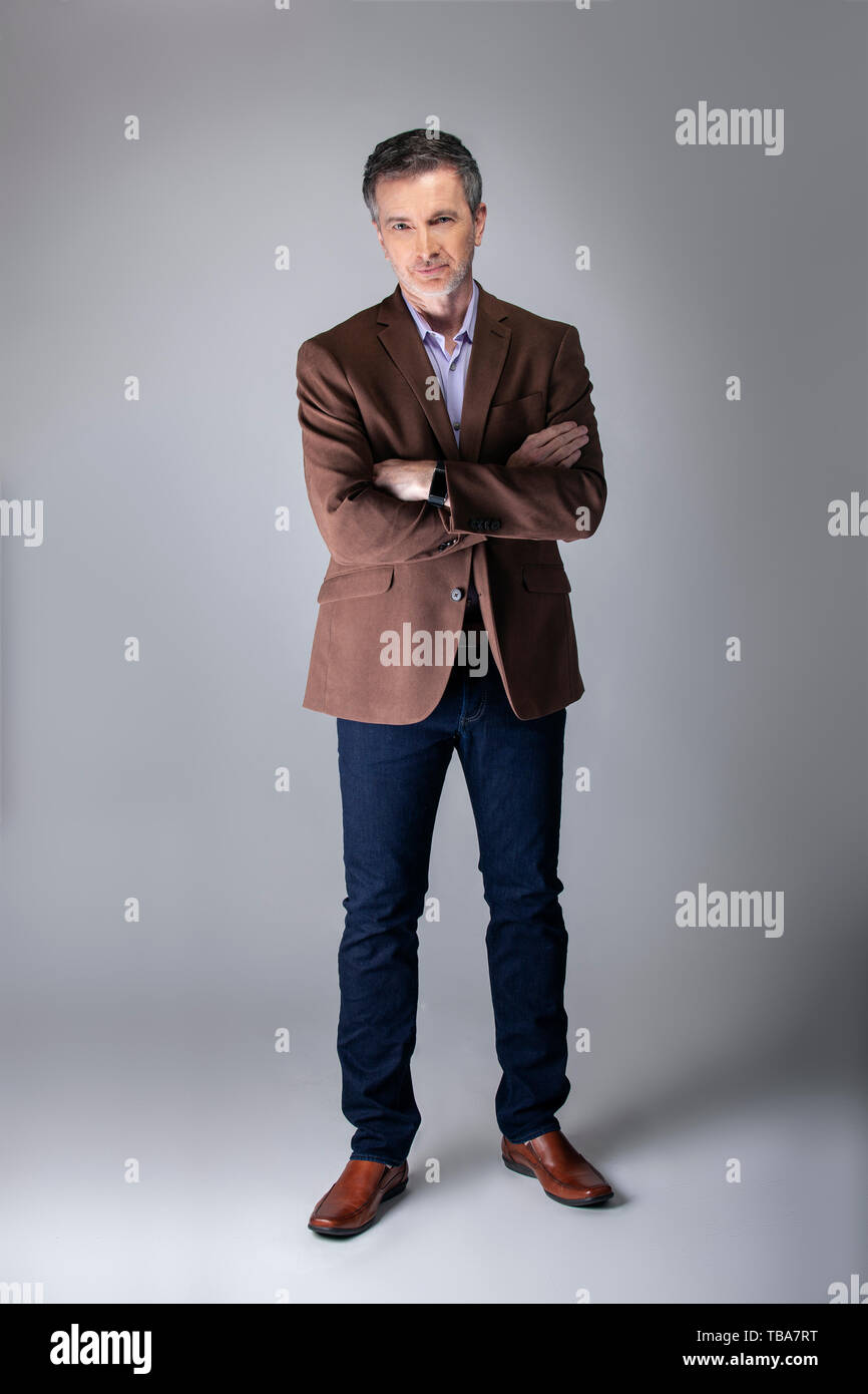Bearded middle aged fashion model posing with business casual style outfit  for mature and confident look. The trendy brown jacket and jeans and facia  Stock Photo - Alamy