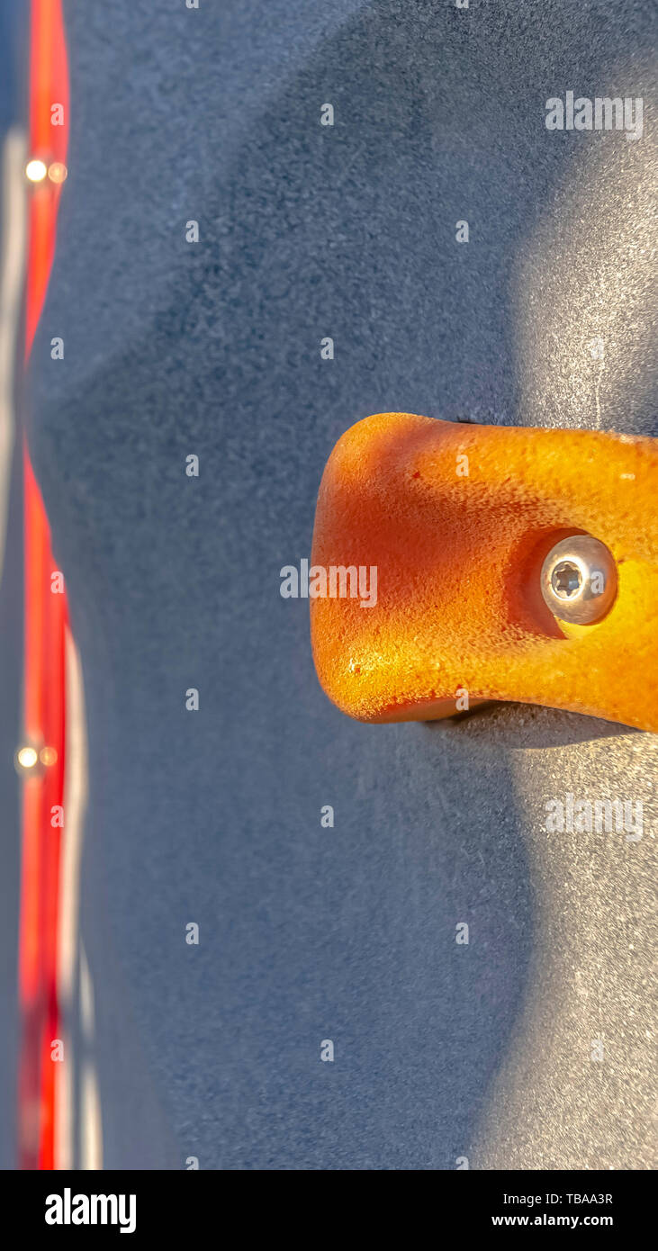 Vertical Bright orange foothold or handhold of a climbing wall at a playground Stock Photo