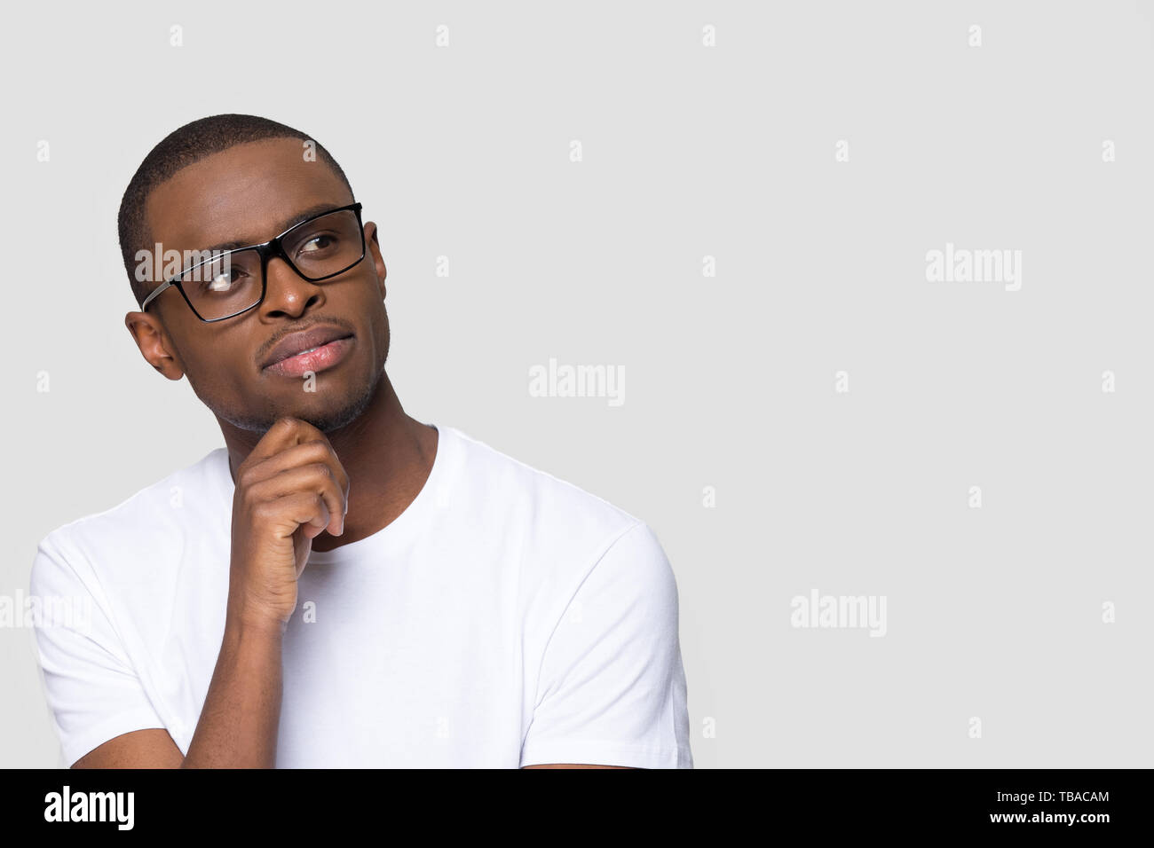 Pensive thoughtful young guy pose on grey wall looking aside Stock Photo