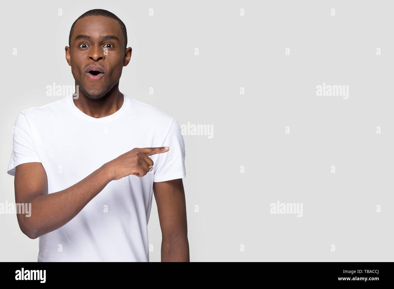 Surprised funny african man pointing aside looking at camera Stock