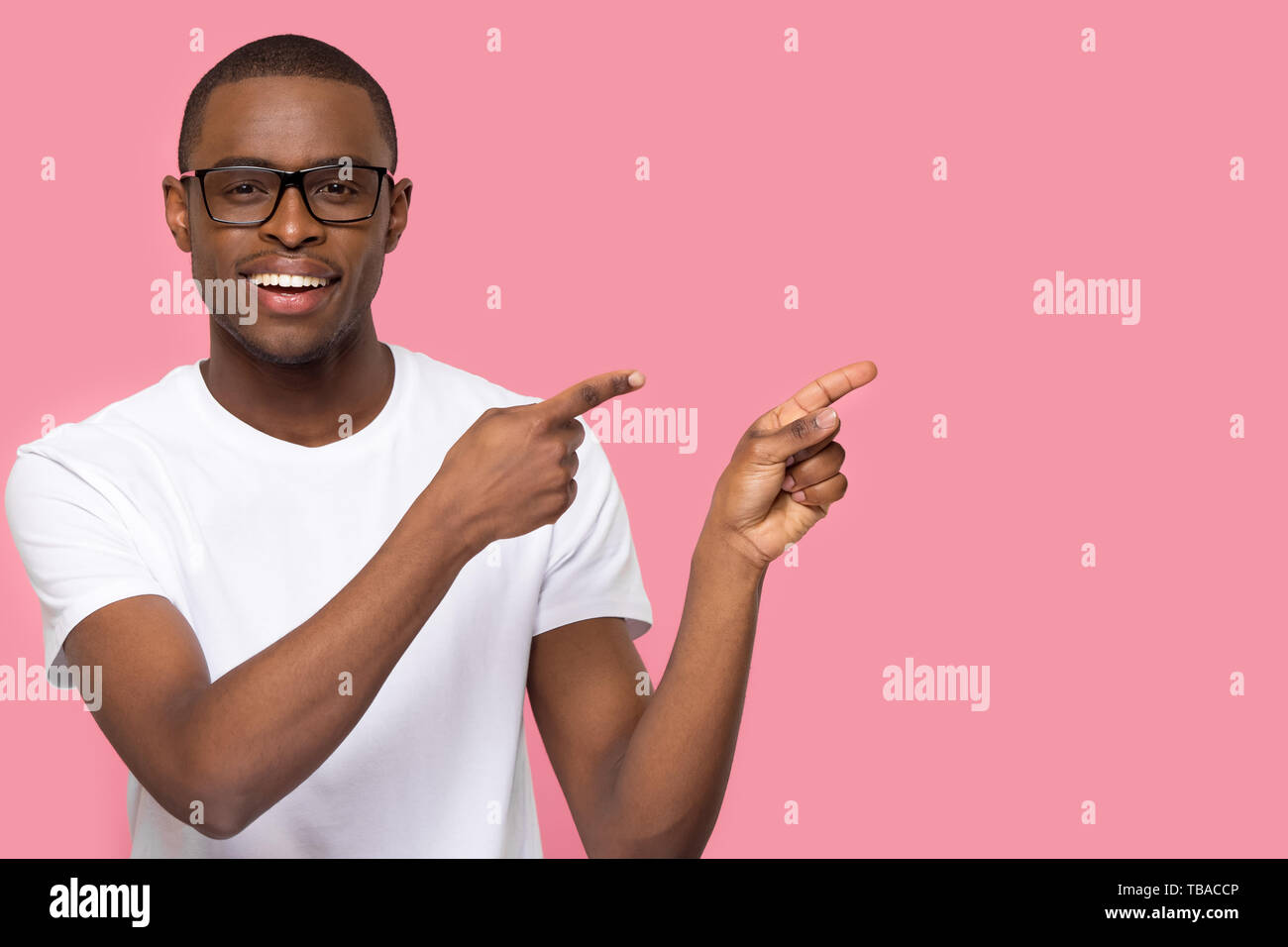 Handsome man in glasses looking at camera pointing aside Stock Photo