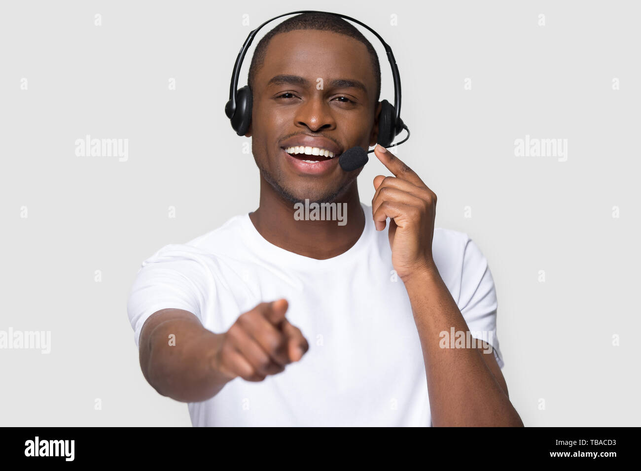 Smiling african man in headset looking pointing finger at camera Stock Photo