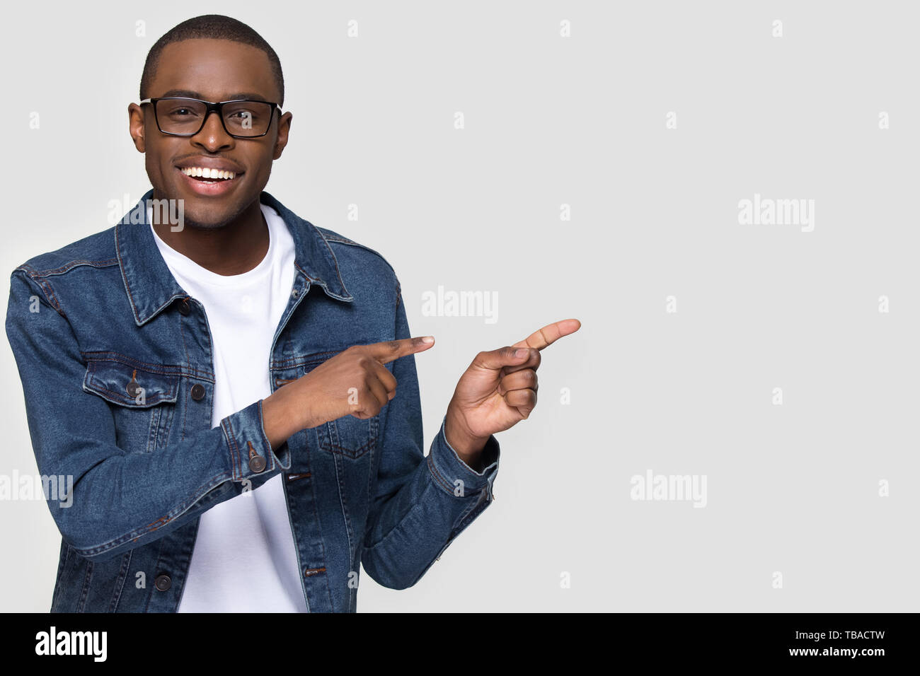 Smiling african man wearing glasses looking at camera pointing aside Stock Photo