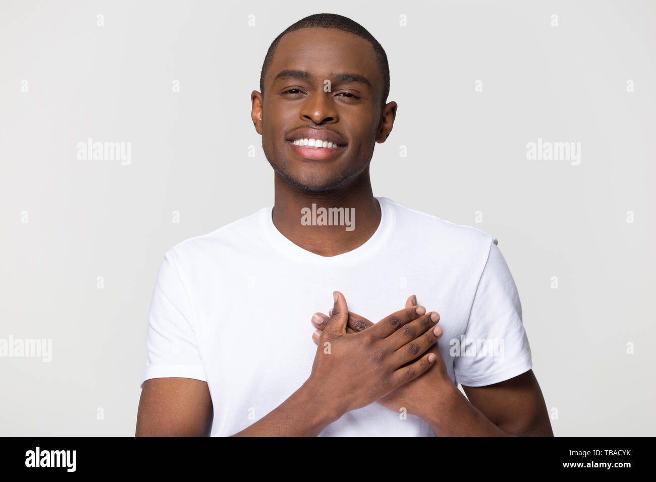 Headshot portrait african male holding hand on heart feels gratitude Stock Photo