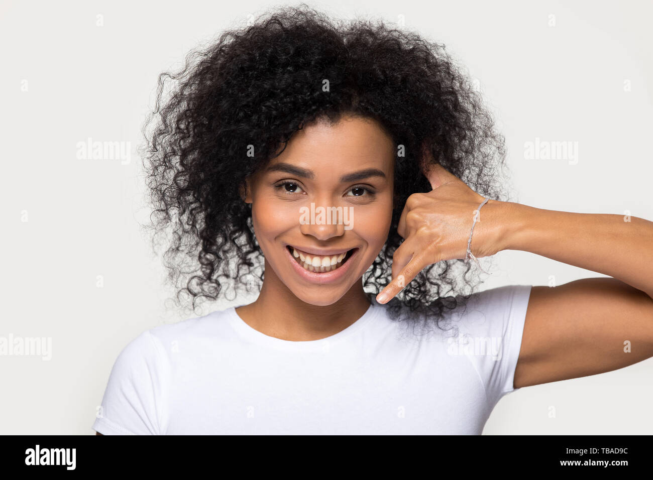 Happy mixed race woman makes call me gesture with hand Stock Photo