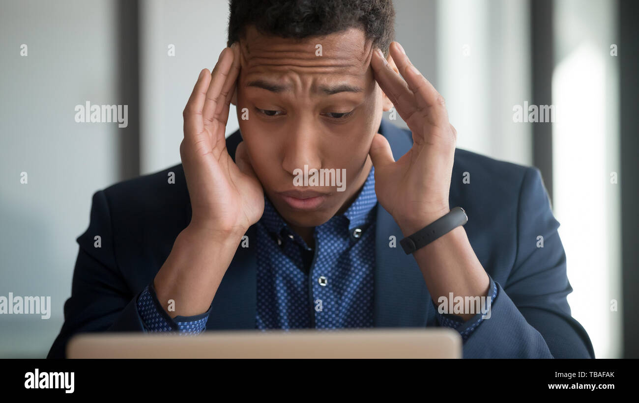 Tired african American employee suffering from headache using laptop Stock Photo