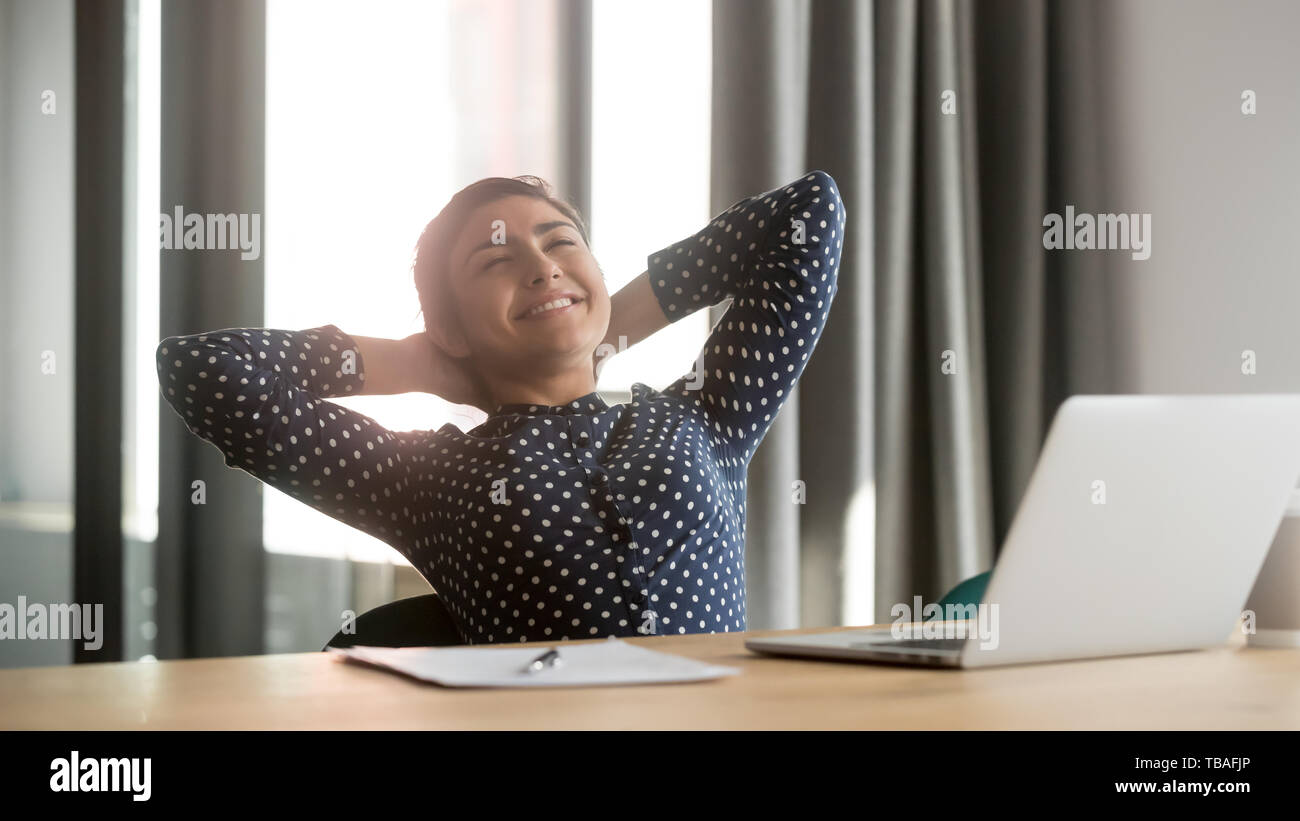 Happy indian woman relax in office chair finishing work Stock Photo