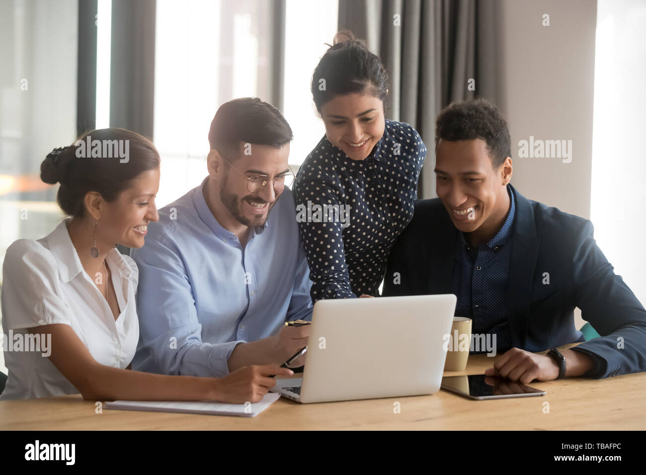 Smiling diverse employees laugh cooperating at laptop in office Stock ...