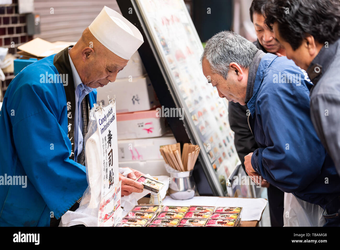 Tokyo, Japan - March 30, 2019: Outer market in Tsukiji Ginza with vendor man closeup selling sushi candy to customers Stock Photo