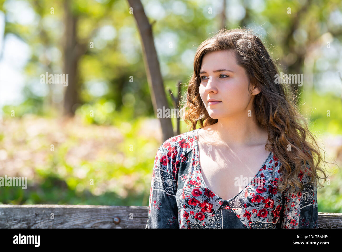 woman-closeup-portrait-of-face-sitting-on-a-wooden-bench-in-sunny