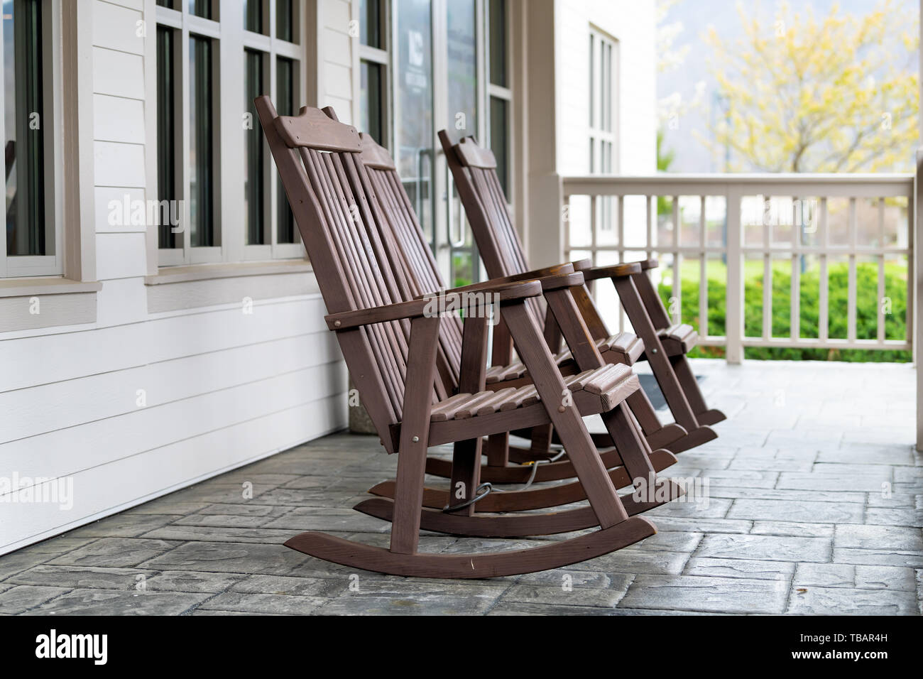 Front porch of house with brown rocking chairs and nobody in traditional american house Stock Photo