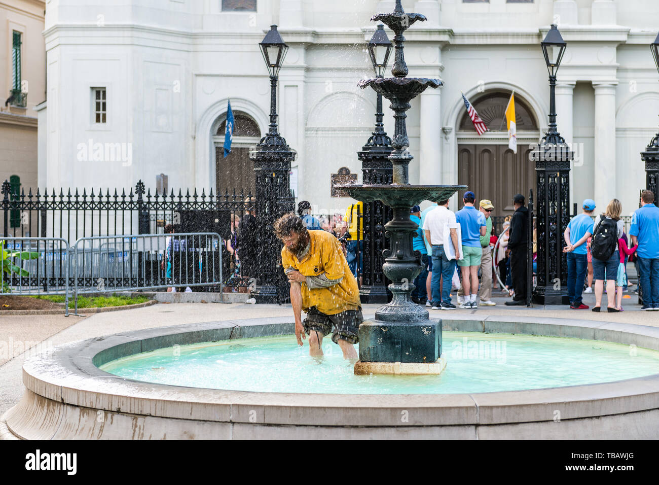 New Orleans, USA - April 23, 2018: Downtown old town Chartres street in Louisiana city with St Louis cathedral church and homeless man picking up chan Stock Photo