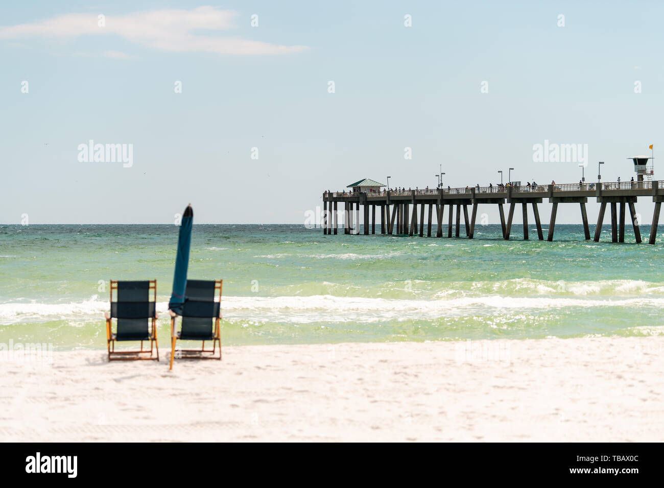 Okaloosa fishing pier in Fort Walton Beach, Florida Panhandle in Gulf of Mexico with two empty beach recliner lounge chairs and umbrella Stock Photo