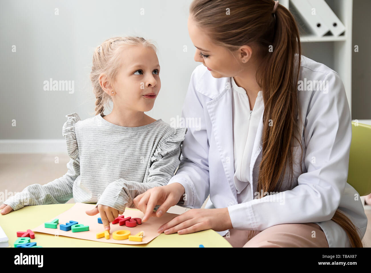 Little girl with speech therapist composing words of letters in office Stock Photo