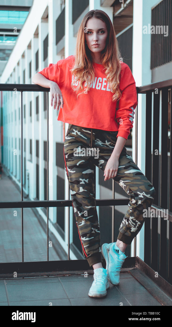 Fashion model wearing red hoodie with the inscription los angeles posing in  the city at parking. Fashion urban outfit. Casual everyday clothing style  Stock Photo - Alamy