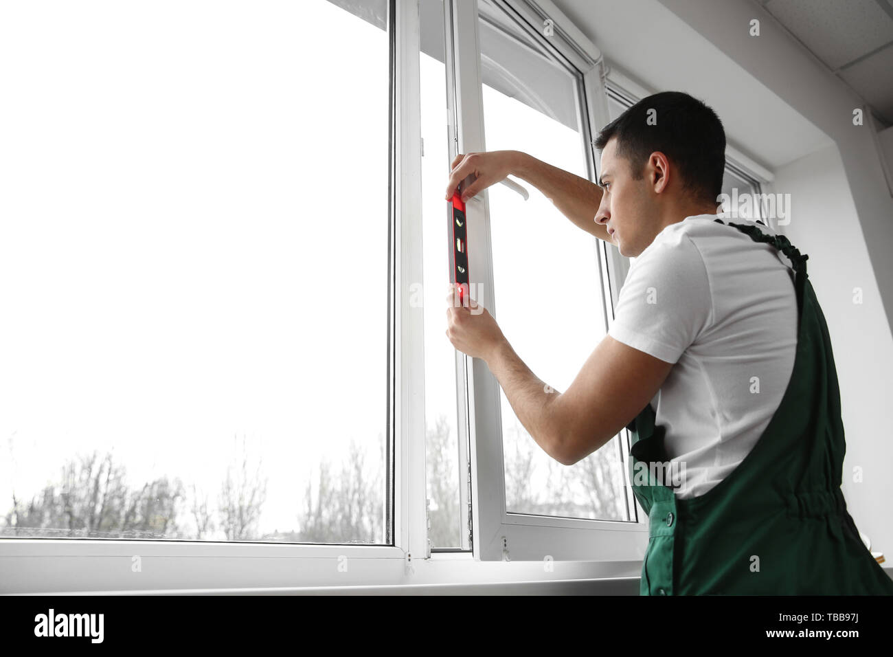 Young worker repairing window in flat Stock Photo